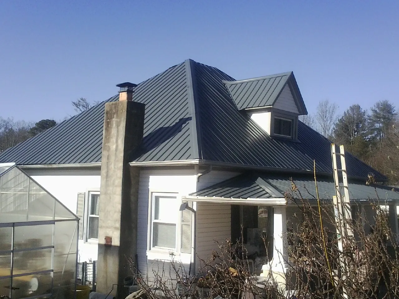 Dark blue standing seam metal roof on a white farmhouse with dormer — Slate & Tile Roof Repair by Roofing Brothers in Slippery Rock