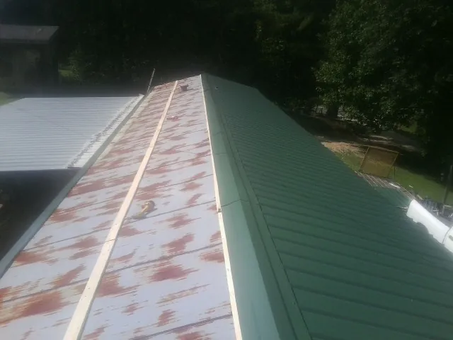 Old rusted panels beside newly installed green metal roofing — Wind Damage Roof Repair by Roofing Brothers in Slippery Rock
