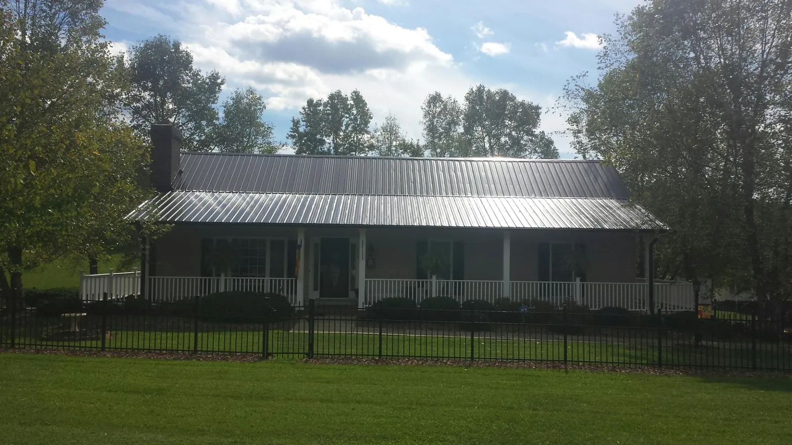 Gray metal roof on a brick ranch with a full width front porch — Gutter Guard Installation work by our crew in Slippery Rock