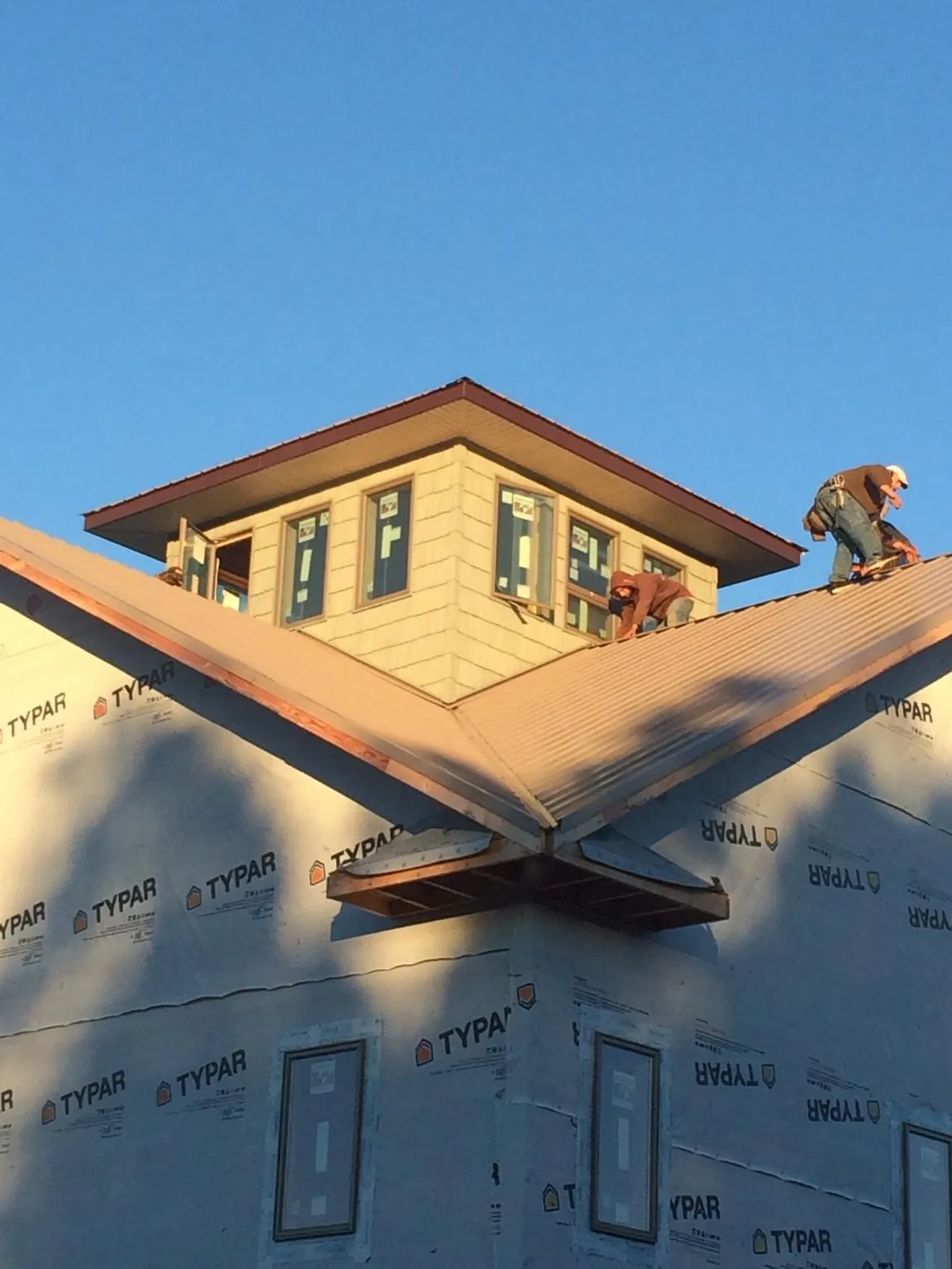 Roofers working around a rooftop cupola on a new metal roof at sunset — Roof Waterproofing in Slippery Rock by Roofing Brothers